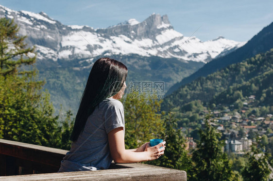 女孩站在阳台上拿着杯子看风景山蒙图片