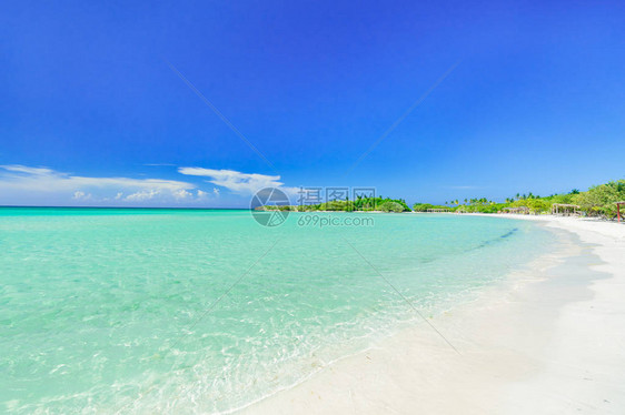 热带白色沙滩和蓝天上宁静的绿松石海洋的迷人景色图片