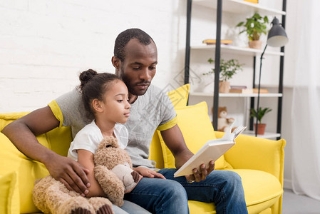英俊的父亲和小女儿在家一起看书的图片