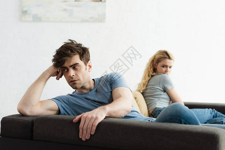 在争吵后坐在金发女人身边的心烦意乱的男人有图片