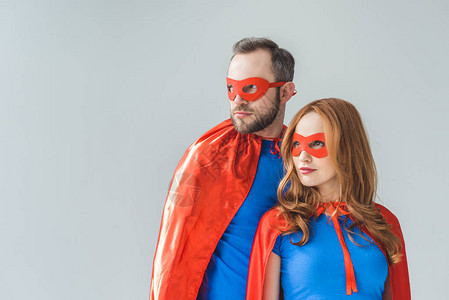 一对夫妇穿着超级英雄服装的情侣站在一起看图片