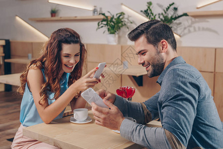 快乐的情侣和智能手机在咖图片