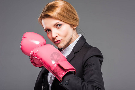 穿着粉红色拳击手套的严肃女商人肖像在图片