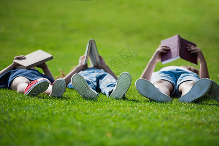 孩子们一起躺在草地上在公园里看书图片