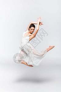 美丽的年轻芭蕾舞女郎穿着白衣服在灰背景图片