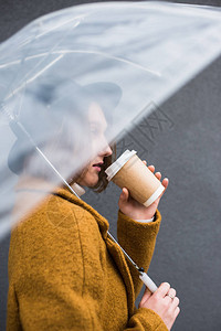 穿着雨伞泡咖啡的帽子时髦女图片