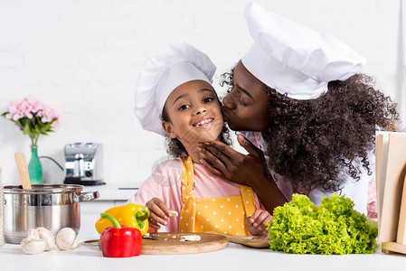 非洲母亲在厨房做饭时亲吻身戴图片