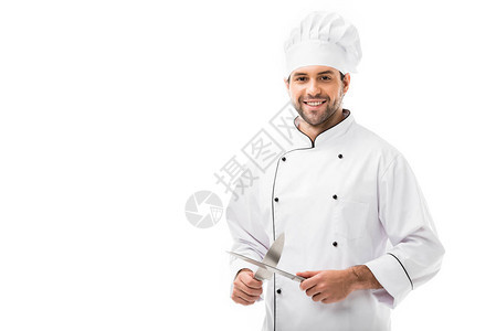 英俊的年轻厨师拿着刀切望着在白色上被图片