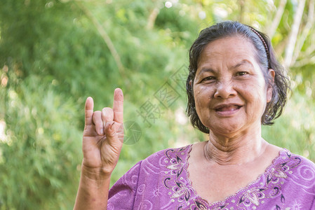 老泰国女人笑着愿意展示我爱你的手牌但错过了成为魔鬼角标志图片