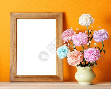 橙色墙上的木制相框与鲜花图片
