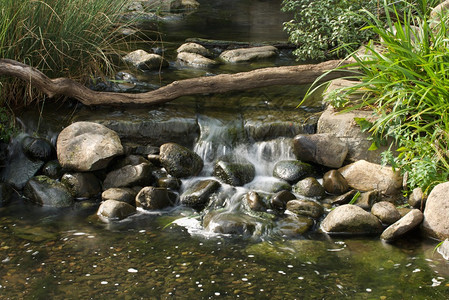 岩石溪流中的瀑布被原木穿过图片