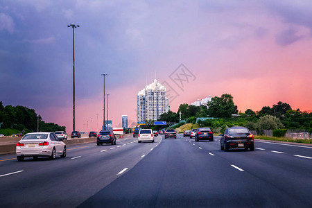 夜间交通在典型繁忙的美国城市的日落晚上公路上的汽车美丽的城市夜景与红色黄色和蓝色的天空云图片