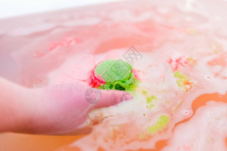 手拿浴盐的绿色和红色泡球洗澡用炸图片