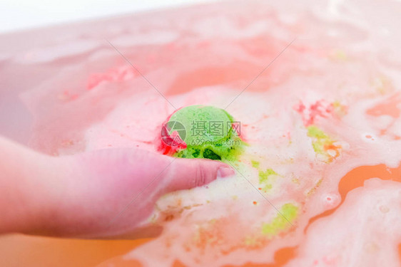 手拿浴盐的绿色和红色泡球洗澡用炸图片