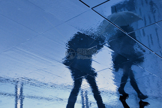 日本东京雨季步行夫妇的雨天路面反射图片