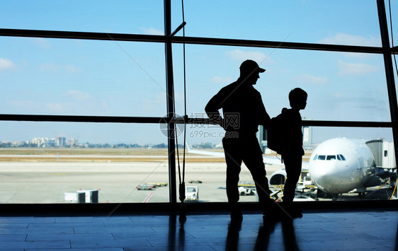 站在机场窗户前的父亲和儿子图片