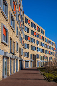 在郊区附近带轻砖和橙色太阳幕的现代公寓楼块图片