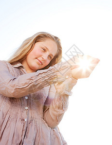 金发年轻女孩拿着太阳握在她的手中图片