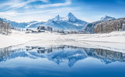 美丽的白色冬季仙境风景在阿尔卑斯山的全景与白雪皑的山峰反映在一个寒冷的晴天与蓝天和云彩图片