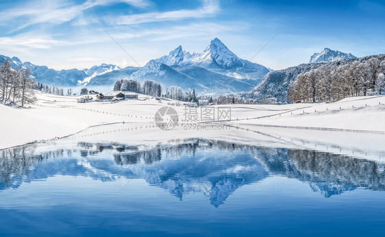 美丽的白色冬季仙境风景在阿尔卑斯山的全景与白雪皑的山峰反映在一个寒冷的晴天与蓝天和云彩图片