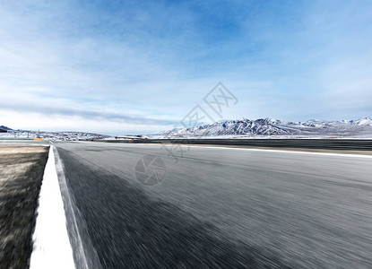 模糊空旷的柏油路和蓝天白云中美丽的雪山图片