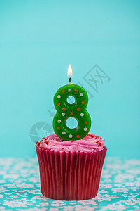 蓝色背景上带有八号蜡烛的生日杯蛋糕图片