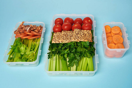 近距离观察装满健康蔬菜肉片和蓝底饼干的食品集装箱安排情况一图片