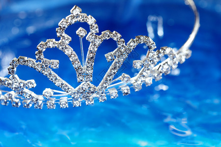 蓝色水背景上镶有钻石的银色王冠的特写照片微距镜头增加了浅景深以图片