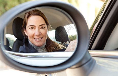一位聪明成熟的女司机在汽车倒后视镜中的倒影图片