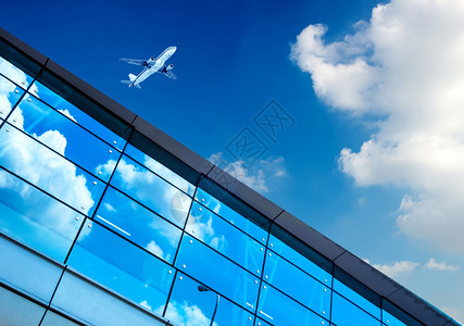 蓝天下的玻璃幕墙和飞机图片