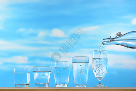 新鲜清洁饮用水从瓶子中倒入玻璃在天空背图片