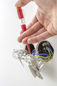 电工在电灯开关上测试电压的特写图片