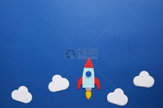 蓝纸背景上的云和火箭带有复制空间图片