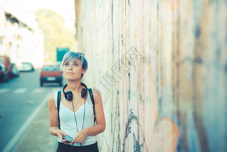 城市里有耳机音乐的年轻美丽短蓝色图片