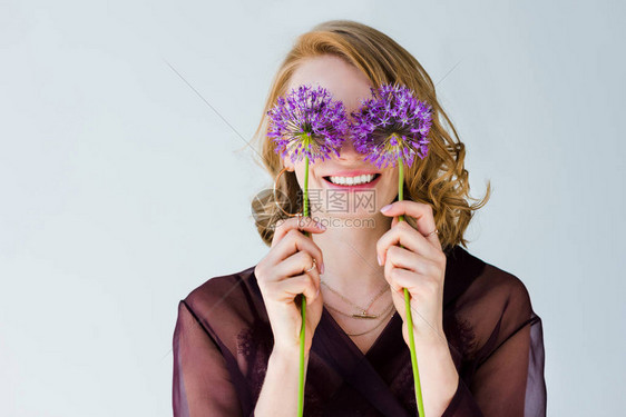 美丽的年轻快乐的年轻女士拿着明亮紫色鲜花图片