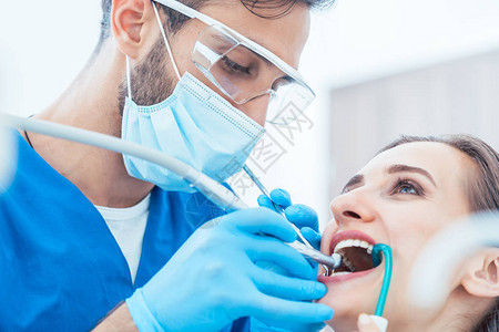 在一位经验丰富和敬业的牙医的现代牙科诊所进行无痛口腔治疗期间图片