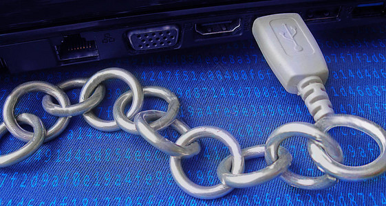区块链技术显示为通过USB连接到计算机的真实金属链蓝色背景覆盖着编码的哈希算法横幅标题或海报是为了说明图片