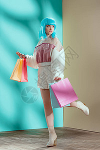 穿着蓝假发的漂亮时装年轻女模特拿着购物袋看一图片