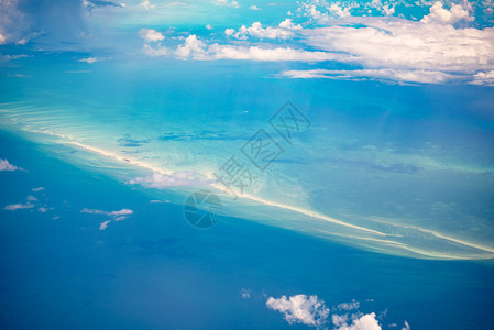 飞机上玩手机巴哈马的空中景象令人惊叹的岛屿沙条和珊瑚礁以及绿海背景