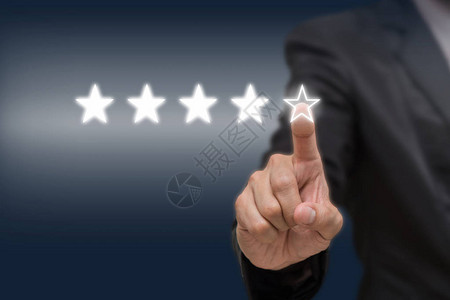商人指着五星符号来提高公司或酒店在暗色调背景下的评级商业评价概图片