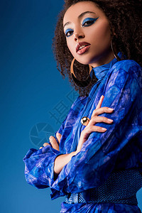 从低角度观察着有吸引力的非洲女穿着时装穿新式服装看着蓝色与世图片