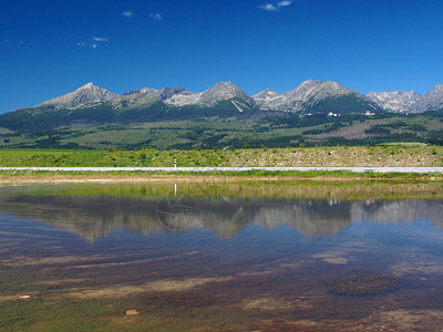 巨大的高塔特拉山峰夏天视图在有路的湖反射在背景中图片