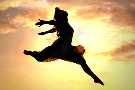 一个女人在粉色日落前跳过空图片