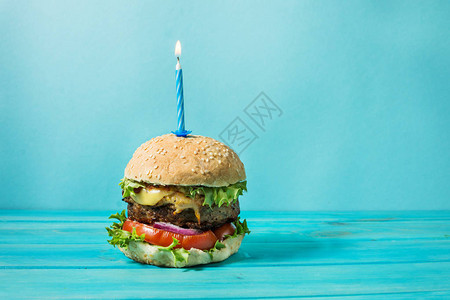 带牛肉的自制汉堡烤肉三明治和点蜡烛在蓝背景的生日派对上点图片