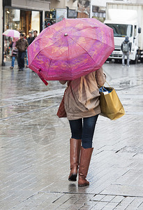 女人在雨中走在市中心的大街上带着雨伞图片