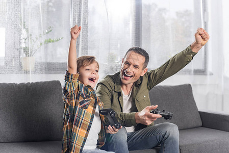 在家玩电子游戏的父亲和儿子兴奋的肖像图片