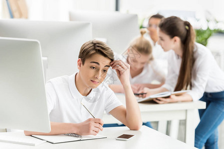 课堂上课时坐在桌边的青少年男孩图片