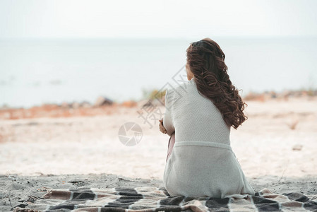 沙滩上独自躺在毯子上的女人的后视图背景图片