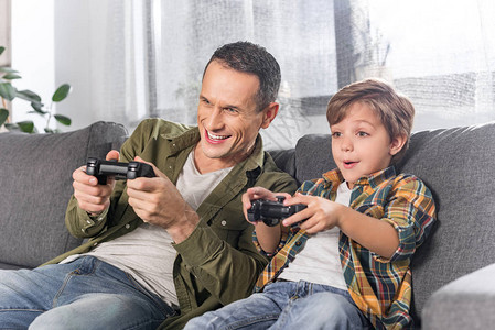 快乐的父亲和儿子在家玩电子游戏的肖像片图片