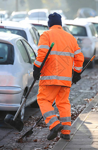 街上清洁工穿着可识别的橙色夹克清扫图片